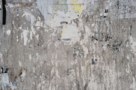 Old bulleting board wall with rests of worn peeled advertising posters, grunge background or textureの写真素材