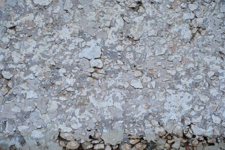 Old traditional limewashed stone wall with peeling plaster, white rustic background or textureの写真素材