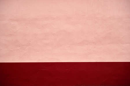 Pink pastel painted concrete wall with dark red red baseboard, abstract background or textureの写真素材
