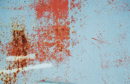 Worn out rusty metallic sheet with layers of blue and red peeling paint, grunge background or textureの写真素材