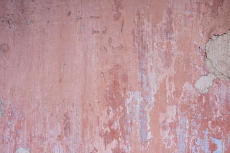 Old distressed wall with pink peeling plaster, grunge background or textureの写真素材