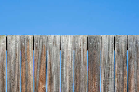 Old wooden planks fence backgorund or texture with blue skyの写真素材