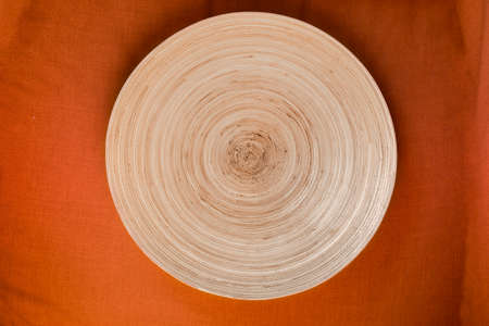 Vegetable fiber handmade decorative round tray on orange tableclorh top viewの写真素材