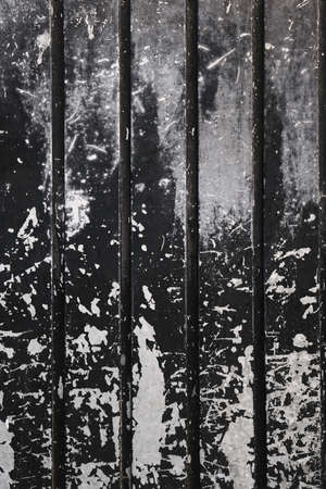 Old metallic shutter with worn out black peeling paint , grunge background or textureの写真素材