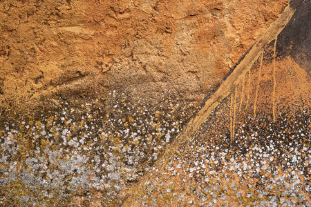 Mouldy ochre colored cement plaster wall with damp, grunge background or textureの写真素材