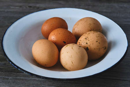 A dish with homegrown fresh kitchen eggs with dirt on the shellの写真素材