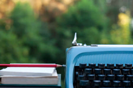 Outdoors vintage desk detail with blank note pad, pencil, books and vintage typewriperの写真素材