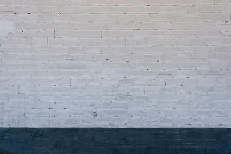 White lime washed brickwall with dark blue  skirting boardの写真素材