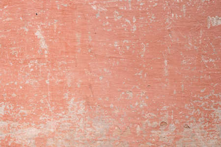 Old distressed wall with worn out salmon pink colored paint, grunge backgroundの写真素材