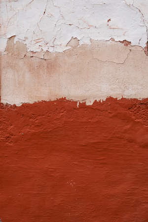 Old plastered wall with red and white worn out paint, architecture detail abstract backgroundの写真素材