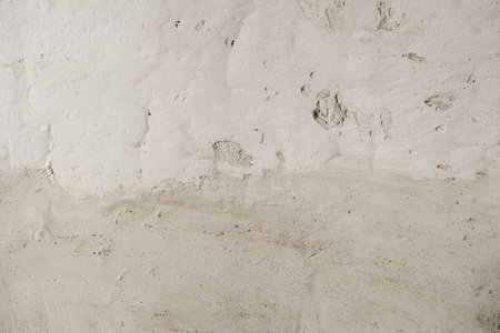 Detail of cement render plaster coating on old white lime washed wallの写真素材