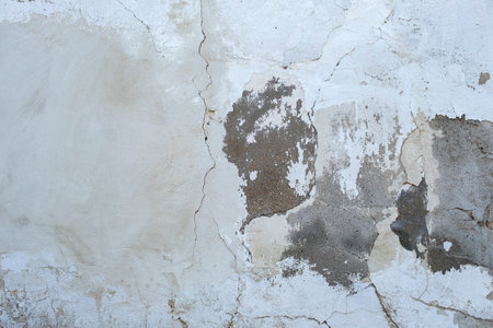 Detail of old cracked cement wall with white limewash plaster coatingの写真素材
