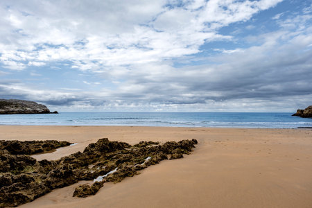Beautiful and quiet sandy beach with sedimentary rocks outcrops in Playa Virgen del Mar, Costa Quebrada, Cantabria, North Spainの写真素材