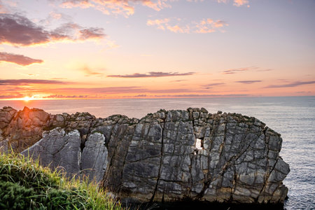 Steep cliff with window-like hollow carved by erosion. Beutiful coastal ladscape at sunset in the Broken Coast of Liencres, Cantabria, Spainの写真素材