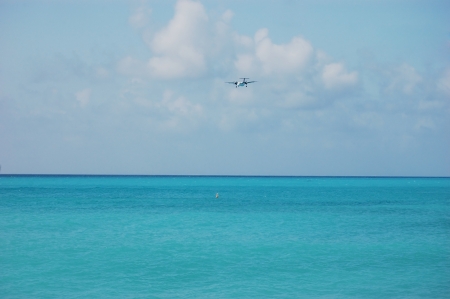 Airplane landing over caribbean beachの写真素材