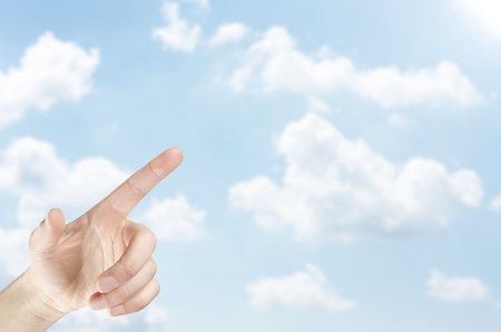 Female hand pointing into the light on the sky の写真素材