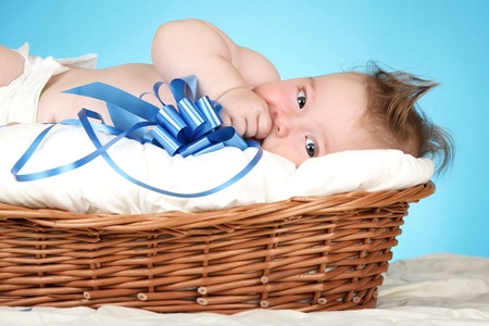 Adorable baby boy in wicker basket with blue bowの写真素材