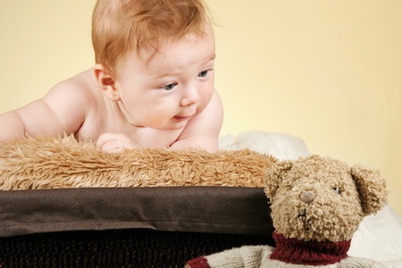 Adorable baby boy looking at his teddy bearの写真素材