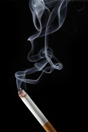 Burning cigarette with smoke on black backgroundの写真素材