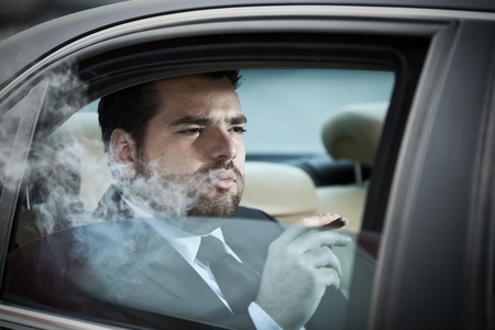 Wealthy man in the back seat of a car smokingの写真素材