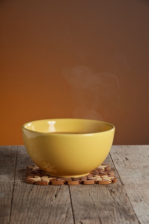 Hot soup in yellow bowl on wooden tableの写真素材