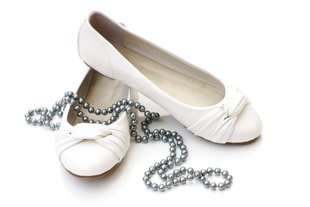White ladies shoes with silver pearl necklace on white backgroundの写真素材