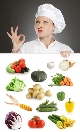 Female chef showing positive gesture over vegetable collectionの写真素材