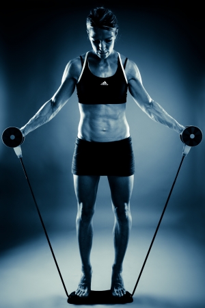 Young fit woman working out, blue toned imageの写真素材