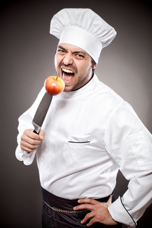 Chef with knife posing against gray backgroundの写真素材