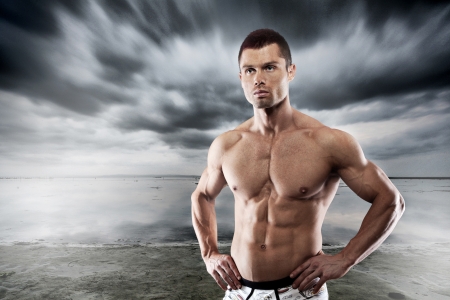 Muscular man posing against dark backgroundの写真素材