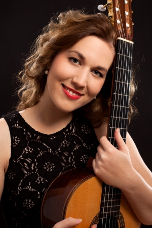 Portrait of young female guitar player against black backgroundの写真素材