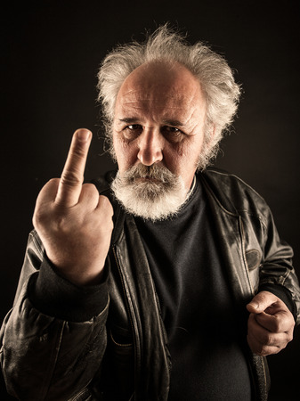 Grumpy man showing middle finger against black backgroundの写真素材