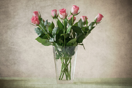Pink roses in vase with old paper textureの写真素材