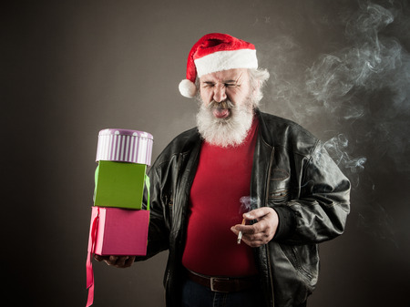 Grumpy Santa Claus with gift boxes and cigaretteの写真素材