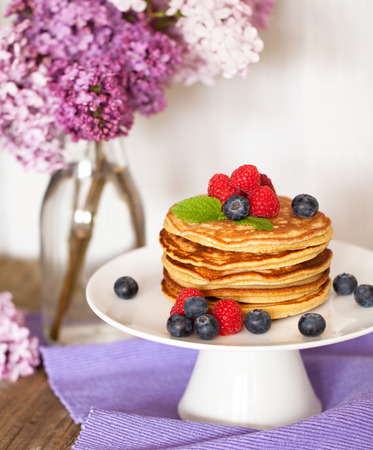 Pile of pancakes with fresh berries on white plateの写真素材