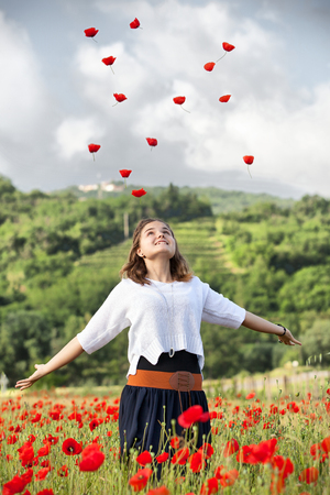 Lovely caucasian teen girl in poppy field in the morningの写真素材