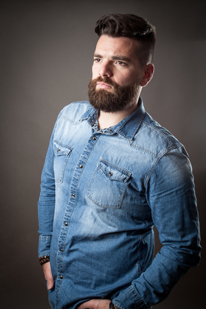 Young caucasian handsome hipster with beard posing in studioの写真素材