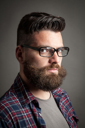 Young caucasian handsome hipster with beard posing in studioの写真素材