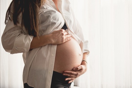Beautiful pregnant woman in white shirtの写真素材