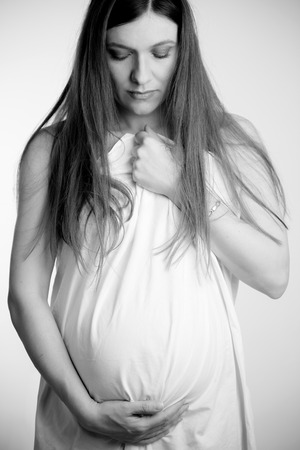 Beautiful pregnant woman in white shirtの写真素材