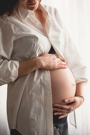 Beautiful pregnant woman in white shirtの写真素材