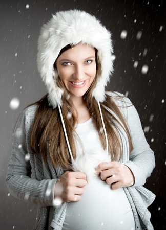 Young beautiful pregnant woman in winter studio shotの写真素材