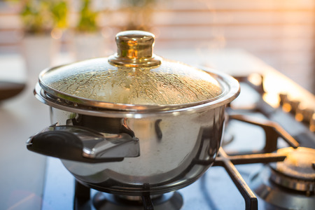 Boiling water in the pot on the stove in the eveningの写真素材