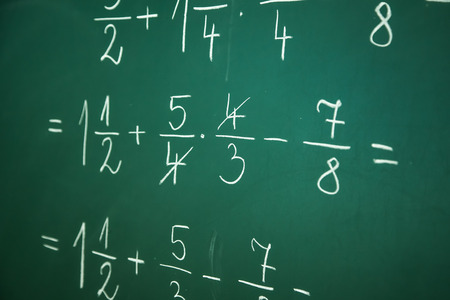 Calcualting with fractions on green blackboard at primary schoolの写真素材