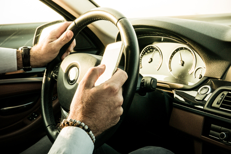 Adult male texting while driving - dangerous behaviourの写真素材