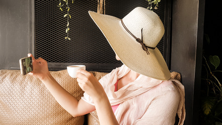 Female tourist with straw hat taking selfie in Phuket townの写真素材