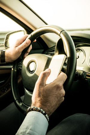 Adult male texting while driving - dangerous behaviourの写真素材