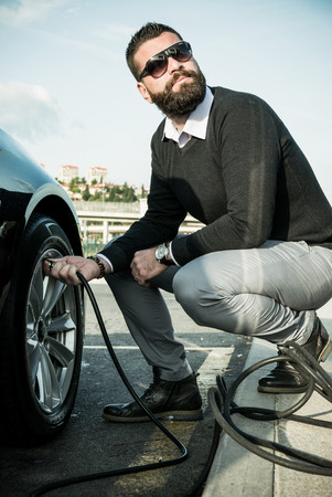 Bearded man checking tire pressure on his carの写真素材