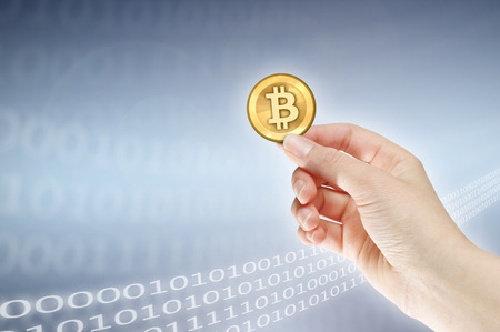 Female hand holding bitcoin against binary backgroundの写真素材