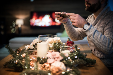 Bearded man taking a photo of decorated christmas tableの写真素材